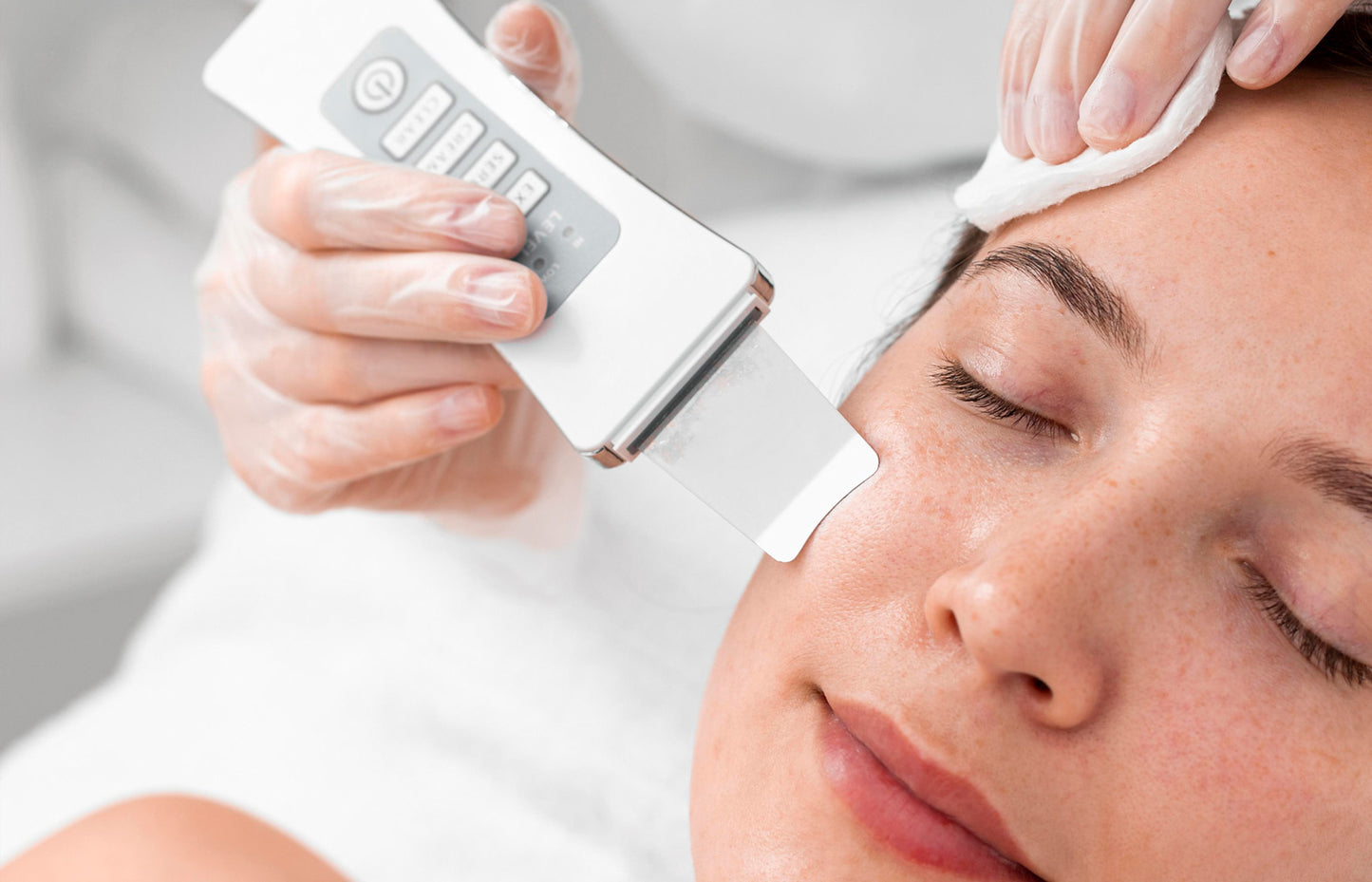 Person receiving a facial treatment with a device on a neutral background