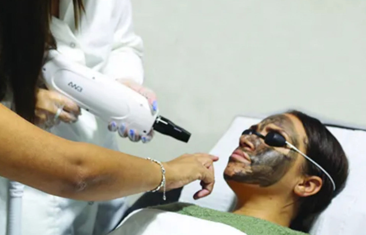 Person receiving a facial treatment with a device from a professional.