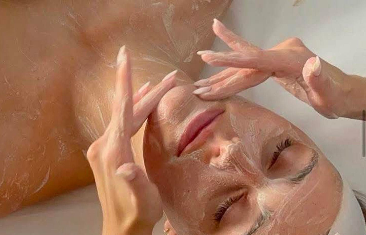 Person applying a facial mask with their hands
