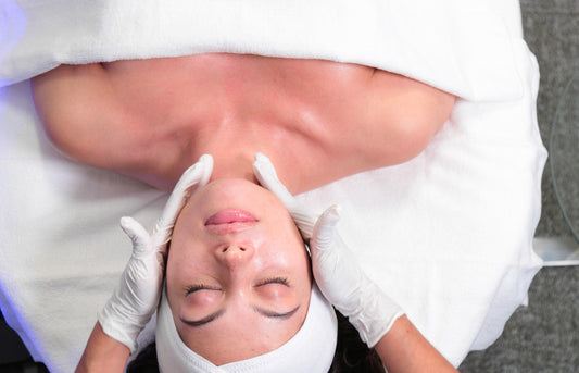 Person receiving a facial treatment with white gloves and towels.