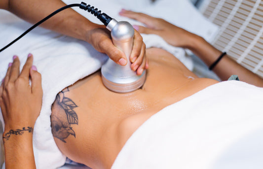 Person receiving a cosmetic treatment with a handheld device on their abdomen.