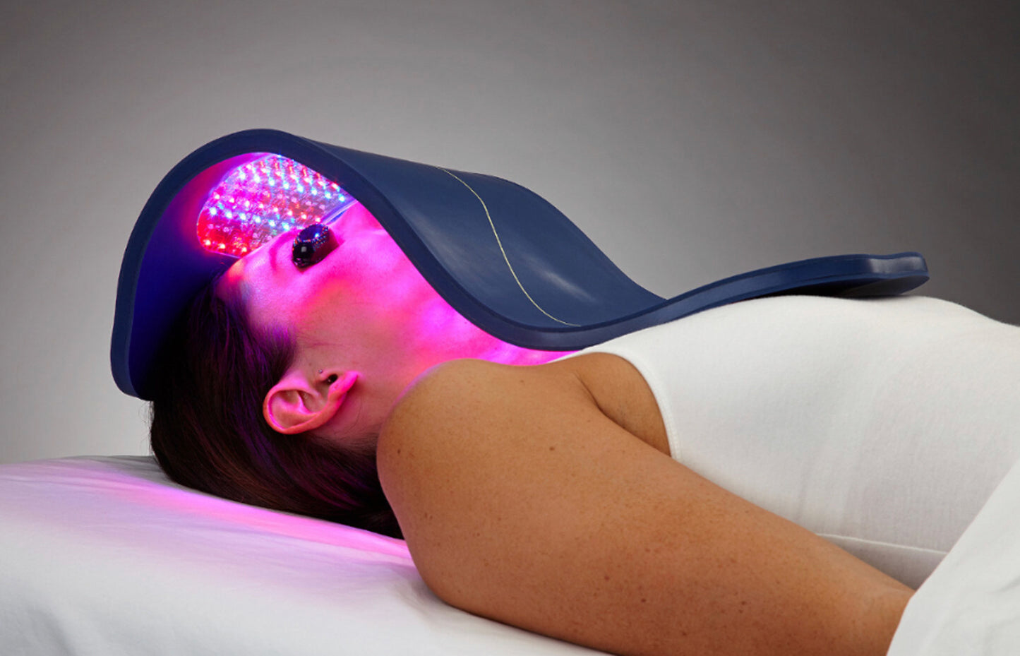 Person receiving LED light therapy on a gray background