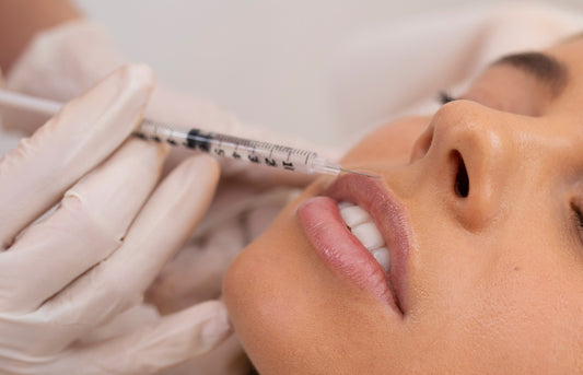 Person receiving a facial injection with a syringe held by gloved hands.