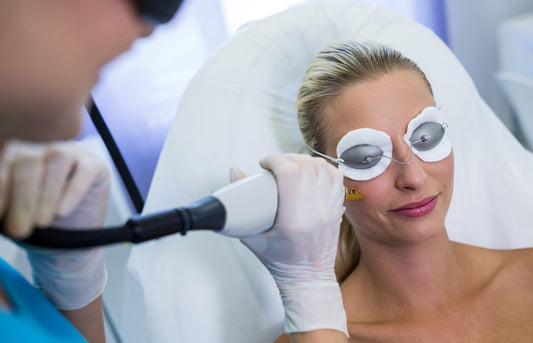 Woman receiving laser treatment with protective goggles on a medical setting.