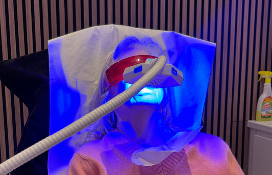 Person wearing a LED face mask with blue light in a room.